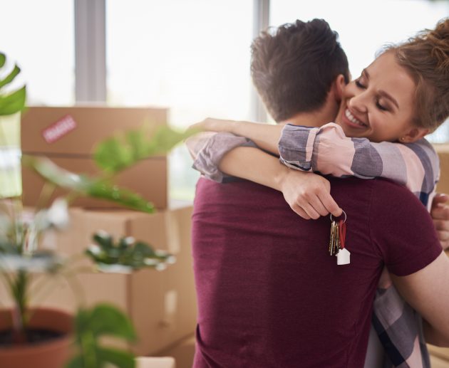 Happy couple with keys of new apartment